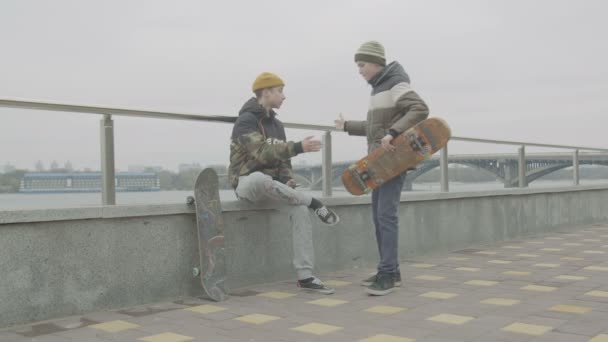 Adolescentes skatistas cumprimentando uns aos outros reunião ao ar livre — Vídeo de Stock