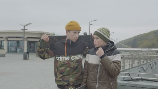 Adolescentes segurando patins conversando andando cidade — Vídeo de Stock