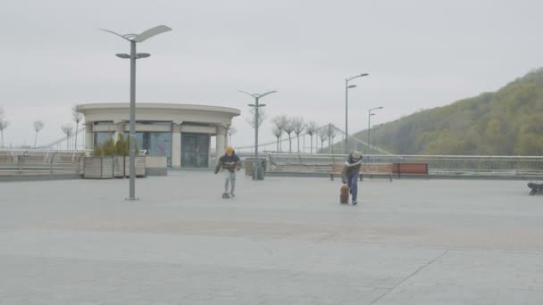 Patinadores adolescentes pisando y rodando en monopatines — Vídeos de Stock