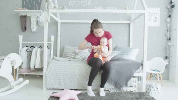 Заботливая мать чистит ребенка в детской комнате — стоковое видео