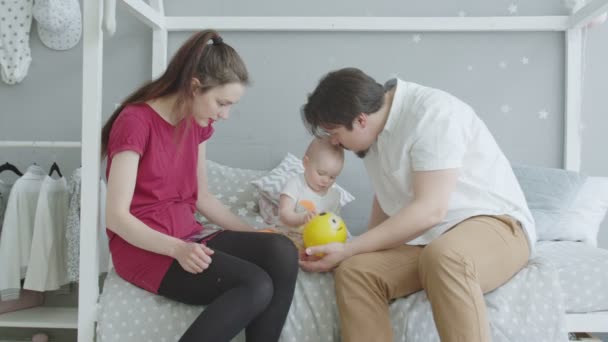 Joyful bebê brincando sentado na cama com os pais — Vídeo de Stock