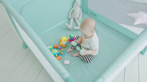 Sevimli bebek kız evde playpen oyuncaklar oynarken — Stok video