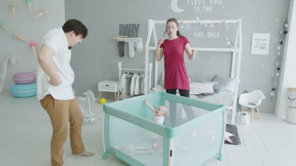 Bebê bonito levantar-se em playpen olhando para os pais — Vídeo de Stock