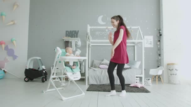 Игривая мама развлекает ребенка сидя в детском кресле — стоковое видео
