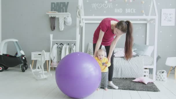 Baby meisje leren om te staan leunend op fitball — Stockvideo