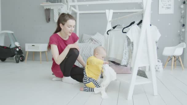 Baby studeren dingen onder Moms toezicht indoor — Stockvideo