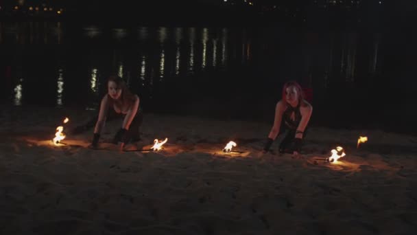 Mujeres malabaristas levantando antorchas encendidas tumbadas sobre arena — Vídeo de stock