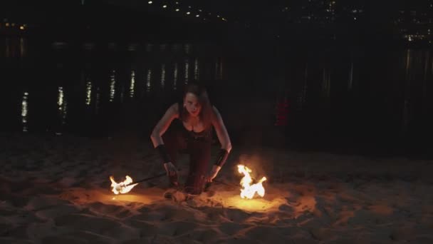 Kvinnlig jonglör höja brinnande ficklampor från sand — Stockvideo