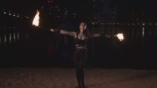 Вогняна дівчина, що виконує навички жонглювання на березі річки — стокове відео