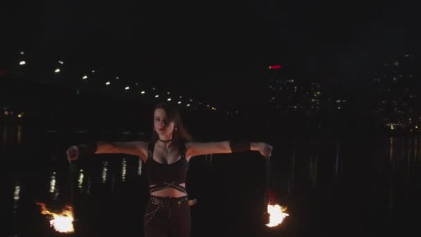 Vrouw kunstenaar jongleren fakkels door de rivier 's nachts — Stockvideo
