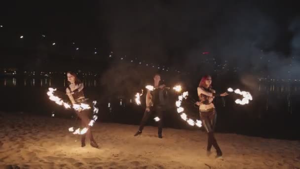 Исполнители Fireshow танцуют с огнем на песке — стоковое видео