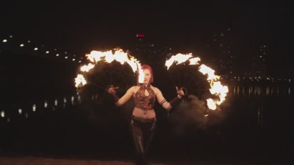 Stijlvolle firegirl Spinning fans tijdens vuurshow — Stockvideo
