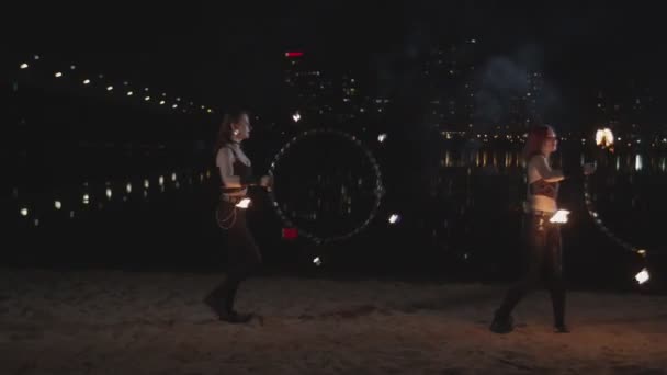 Belles firegirls jonglant cerceaux de feu sur le bord de la rivière — Video