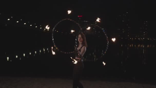 Artiste féminine tordant cerceaux de feu pendant les feux d'artifice — Video