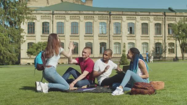 Estudiantes multiétnicos dando alta cinco reunión en el césped — Vídeos de Stock