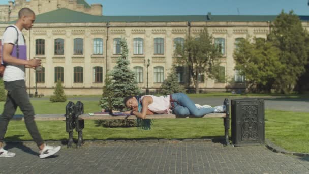 Hombre estudiante despertando amigo durmiendo en parque — Vídeos de Stock