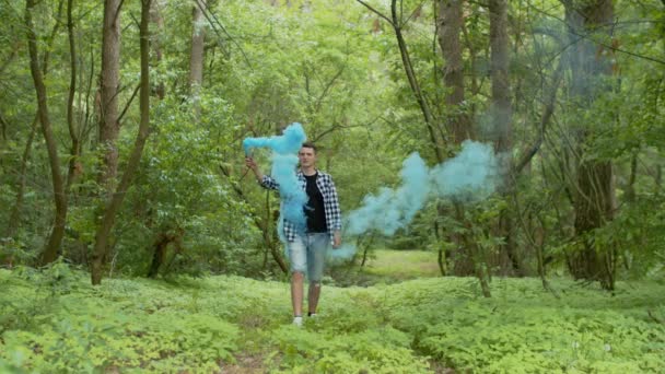 Young man with smoke bomb walking in forest — 비디오