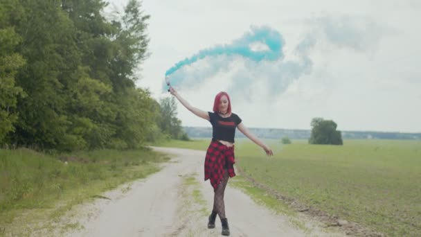Щаслива жінка танцює, тримаючи димову бомбу на відкритому повітрі — стокове відео