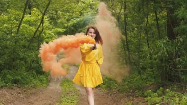 Donna sorridente che cammina con una bomba fumogena nella foresta — Video Stock