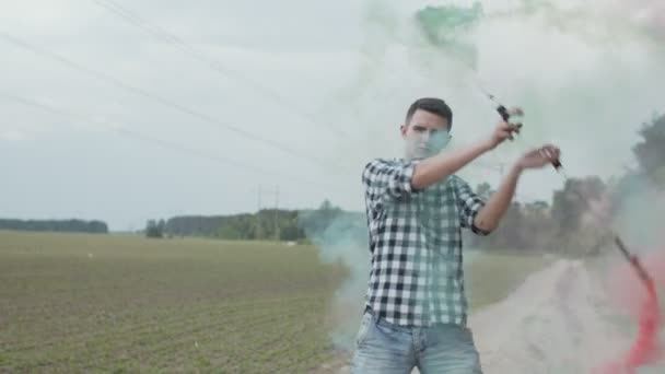 Młody człowiek przędzenie kolorowe dymu poi na wiejskiej drodze — Wideo stockowe