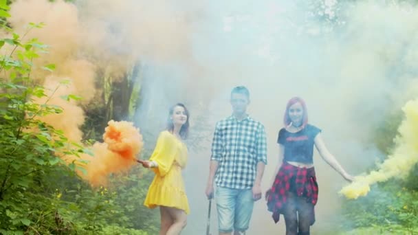 Яркие молодые люди прячутся в цветном дыму на открытом воздухе — стоковое видео