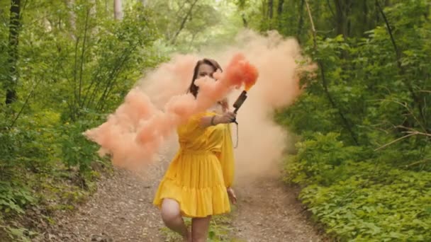 Femme heureuse marchant dans la fumée de couleur à travers la forêt — Video