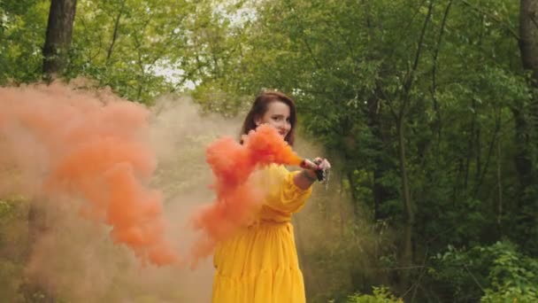 Жінка з димовою бомбою, що йде лісовою стежкою — стокове відео
