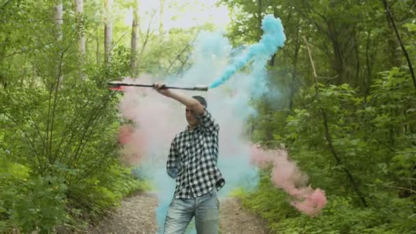 Male juggling colored smoking staff in greenwood — Stock Video