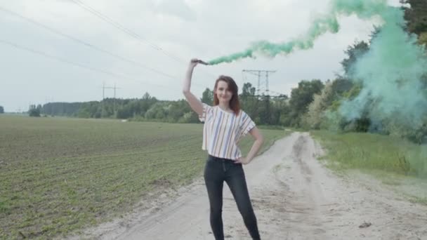 Kobieta chodzenie po wiejskiej drodze przez kolorowy dym — Wideo stockowe