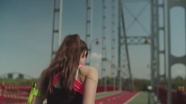 Şehir köprüsünde antrenman yaparken koşan genç bir bayan. — Stok video