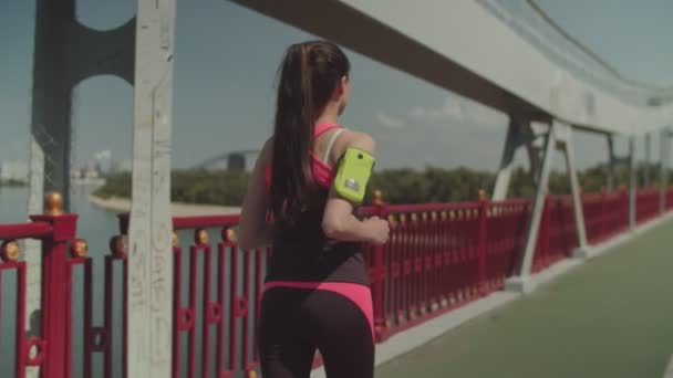 Atleta Spoty en forma mujer corriendo a lo largo del puente de la ciudad — Vídeos de Stock