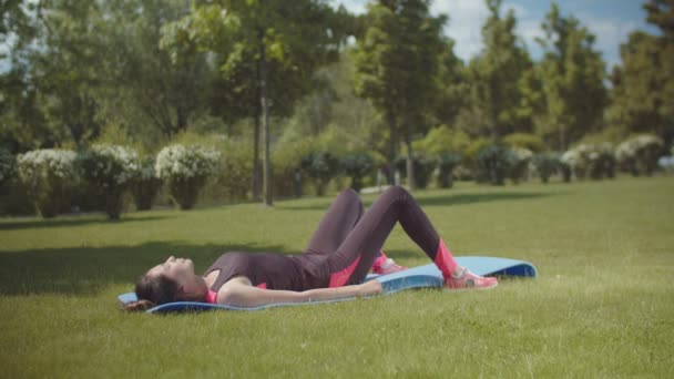 Spory kvinna tränar på Fitness matta i parken — Stockvideo