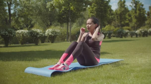 Adatta addominali da allenamento donna sul tappeto sportivo nel parco cittadino — Video Stock