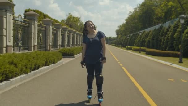 Alegre patinaje femenino a velocidad en el sendero del parque — Vídeo de stock