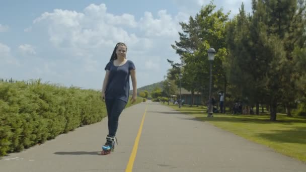 Молода жінка ролик насолоджується фрірайдом у зеленому парку — стокове відео