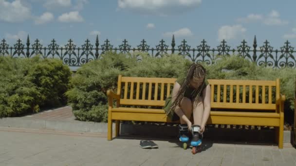 Женщина-каток снимает ролики со скамейки — стоковое видео