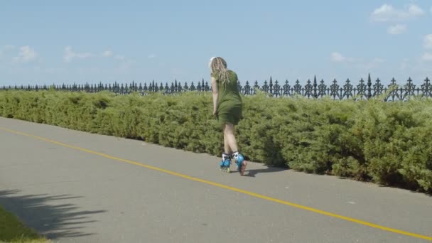 Женщина-роллер едет в парке в обратном направлении — стоковое видео