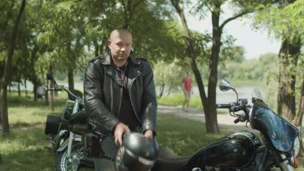 Serious biker dressing up black leather jacket — Stock Video