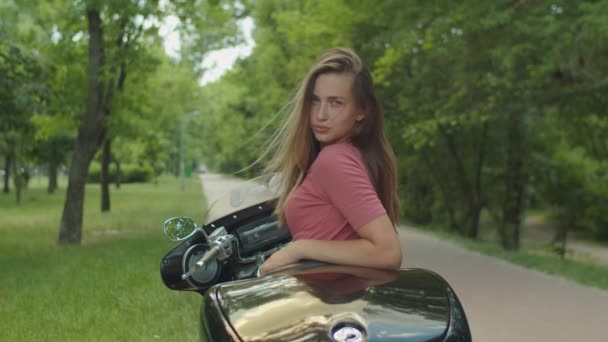 Portret uroczej dziewczyny siedzi na motocyklu — Wideo stockowe