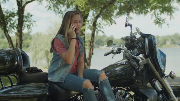Chatten op telefoon schattig meisje zittend op motorfiets — Stockvideo