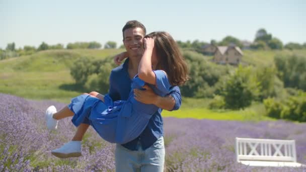 Hombre alegre girando mujer amada en el campo floral — Vídeo de stock