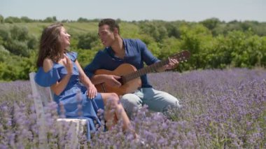 Gitar çalan ve doğada kadına şarkı söyleyen adam