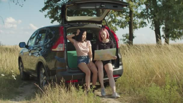 Señoras con mapa en busca de dirección en el viaje en coche — Vídeo de stock