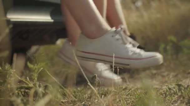 Женские ноги свисают с багажника машины в летний день — стоковое видео