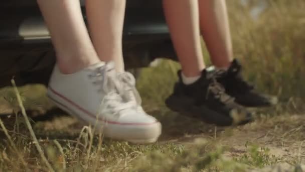 Araba bagajından sarkan spor ayakkabılı kadın bacakları — Stok video