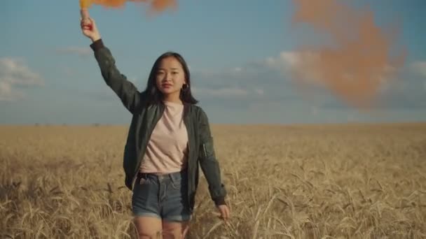 Menina asiática criando nuvens de fumaça colorida no campo — Vídeo de Stock