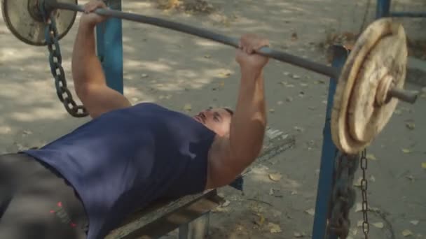 Uomo atletico che fa esercizi con bilanciere in panchina — Video Stock
