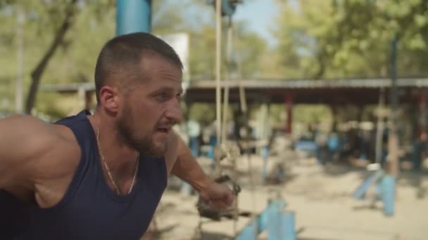 Porträt eines fitten Mannes, der an einer Seilkreuzung trainiert — Stockvideo
