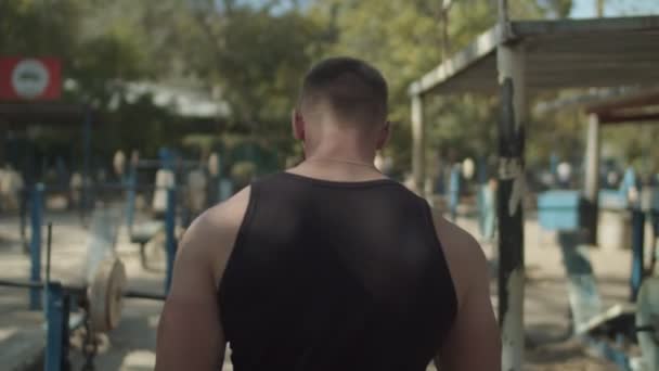 Confident bodybuilder walking through outdoor gym — Stock Video