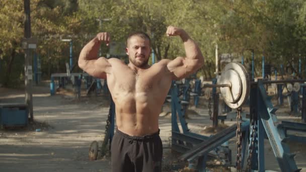 Fisicoculturista sin camisa haciendo doble bíceps pose — Vídeos de Stock